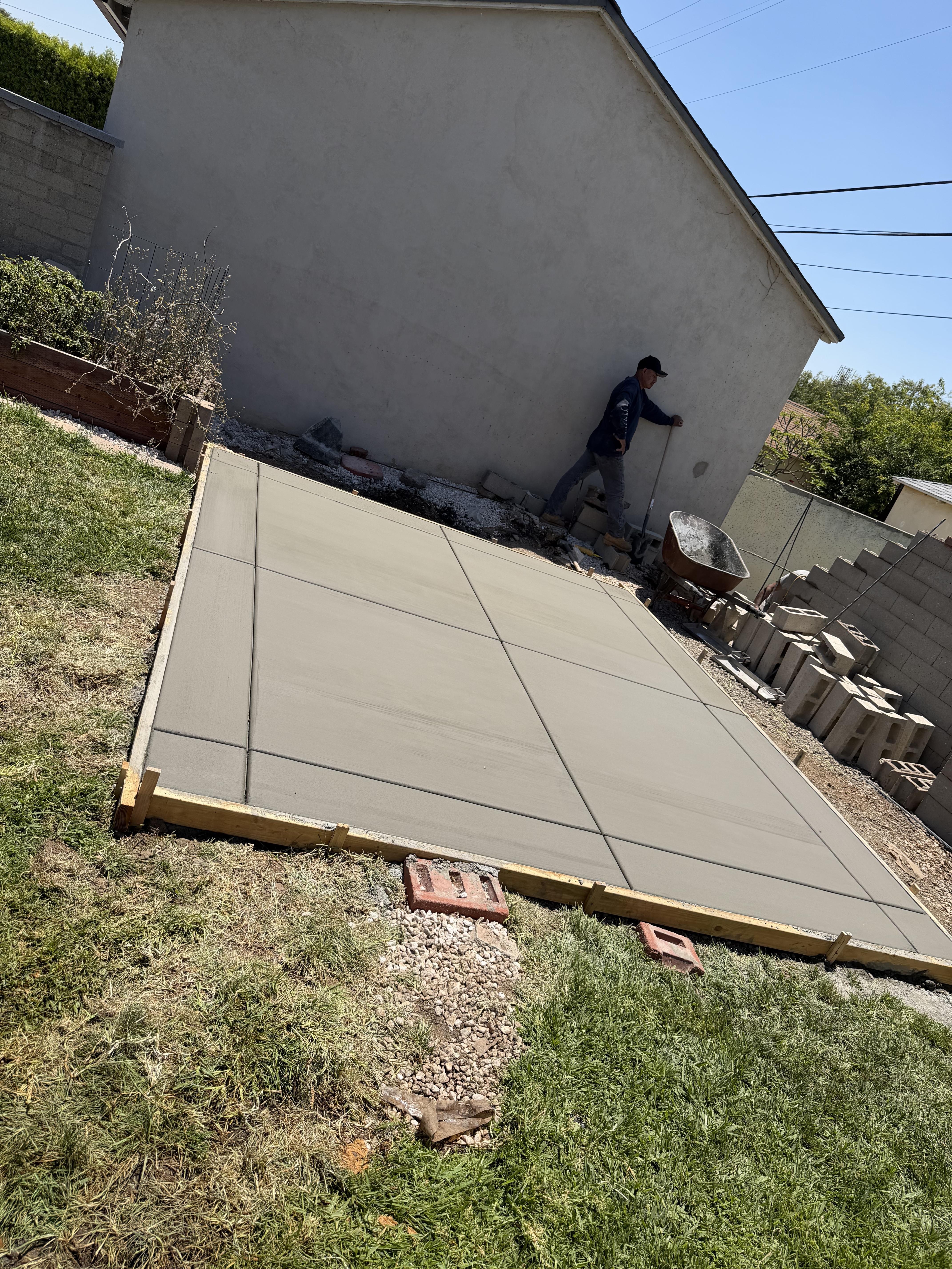 Freshly finished rectangular concrete slab with control joints during a residential backyard project
