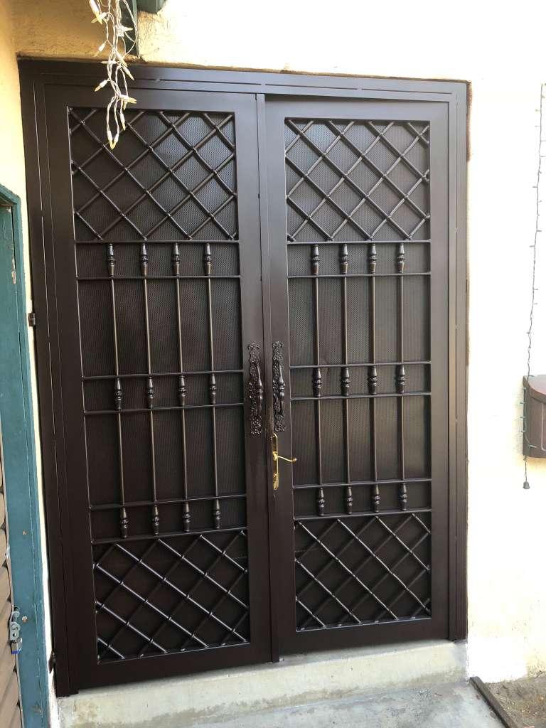 Custom black metal double security doors with diamond latticework, vertical bars, and decorative hardware