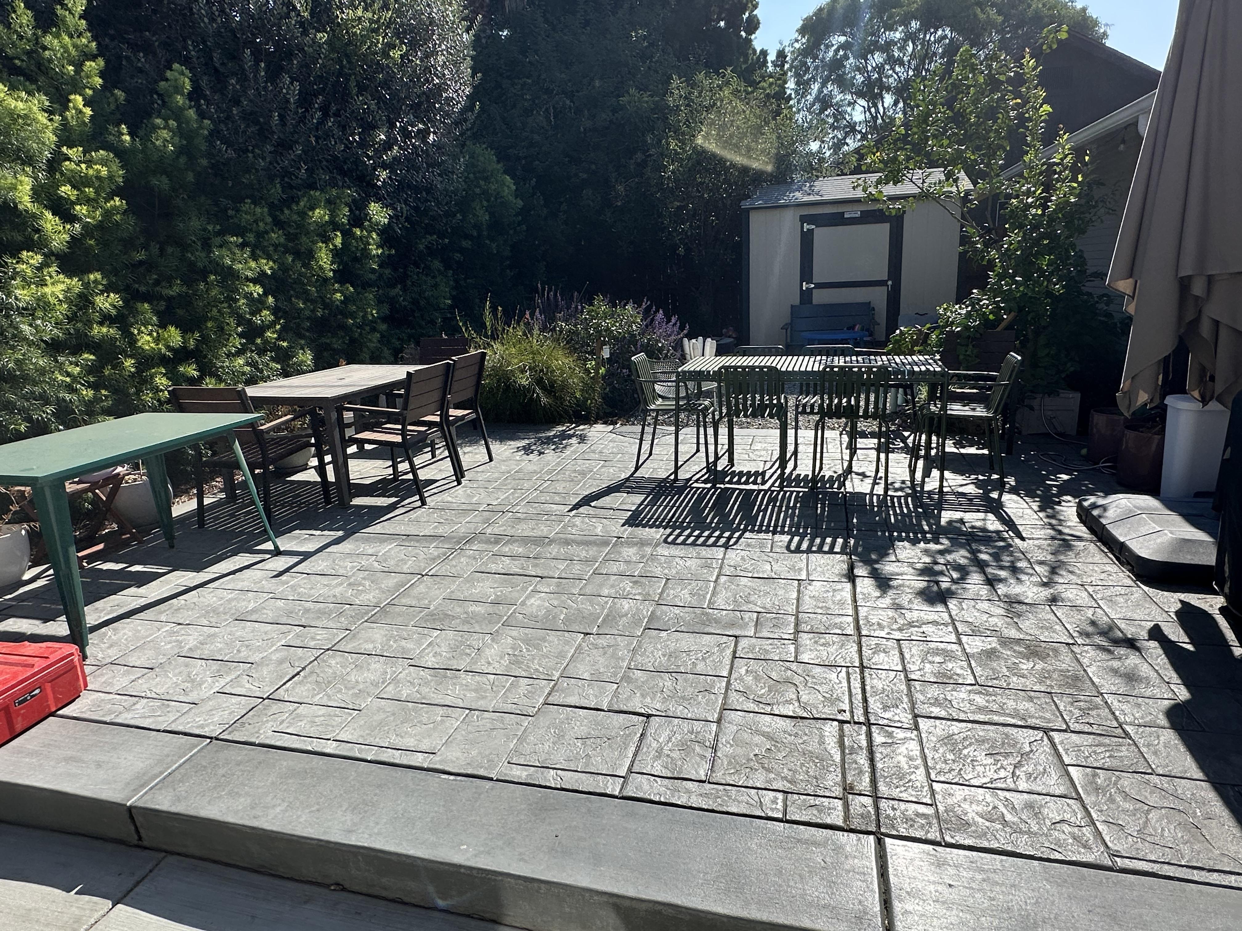 Finished stamped concrete backyard patio furnished with outdoor tables and chairs